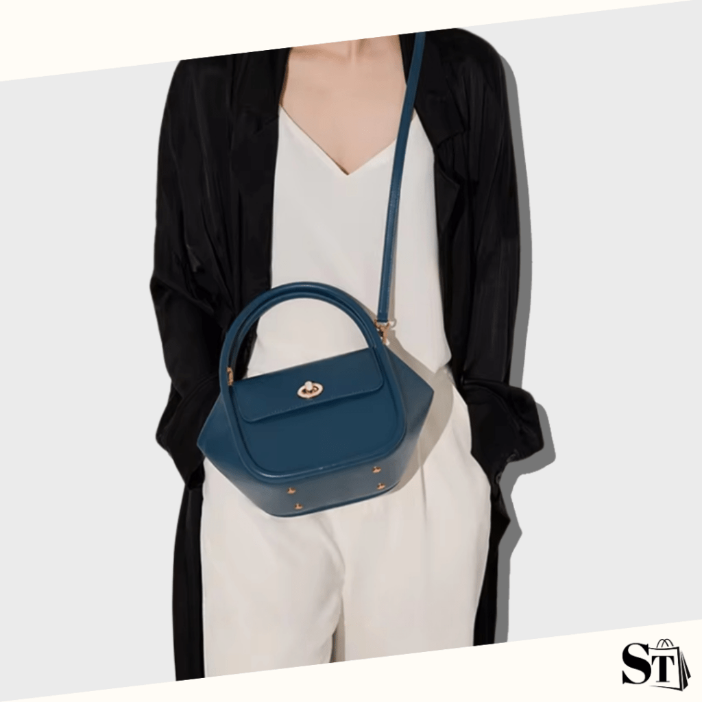 Jeune femme habillée chic avec un blazer noir et un ensemble blanc cassé portant un sac à main tendance en cuir bleu navy en bandoulière