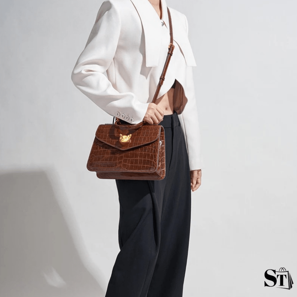 Jeune femme habillée chic portant un sac chic marron à motifs crocodile avec détails dorés